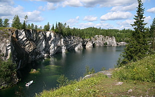gray rocky cliff near the lake under the cloudy skies